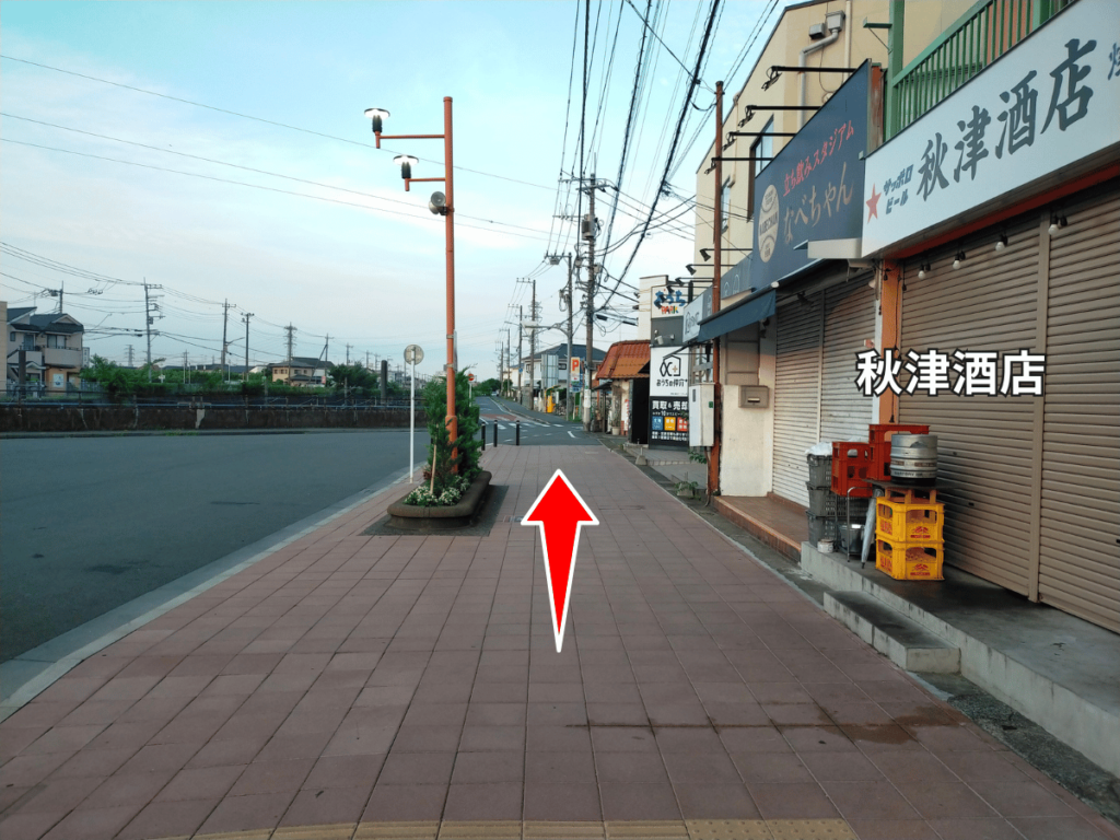 秋津酒店前をまっすぐ進む道順。直進方向を示す赤い矢印。