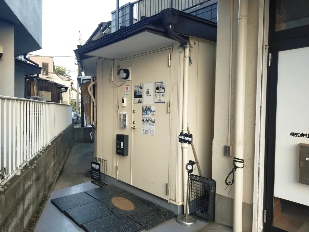 秋津のパーソナルトレーニングルームの入り口ドア。ウェルカムマットと看板が見える最終目的地。